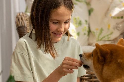 smiling girl feeding her dog a pill